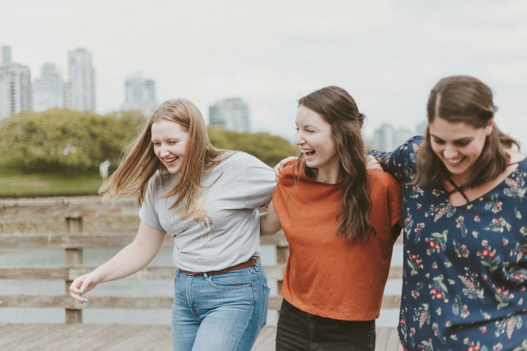 Three friends walking arm in arm along a waterfront
