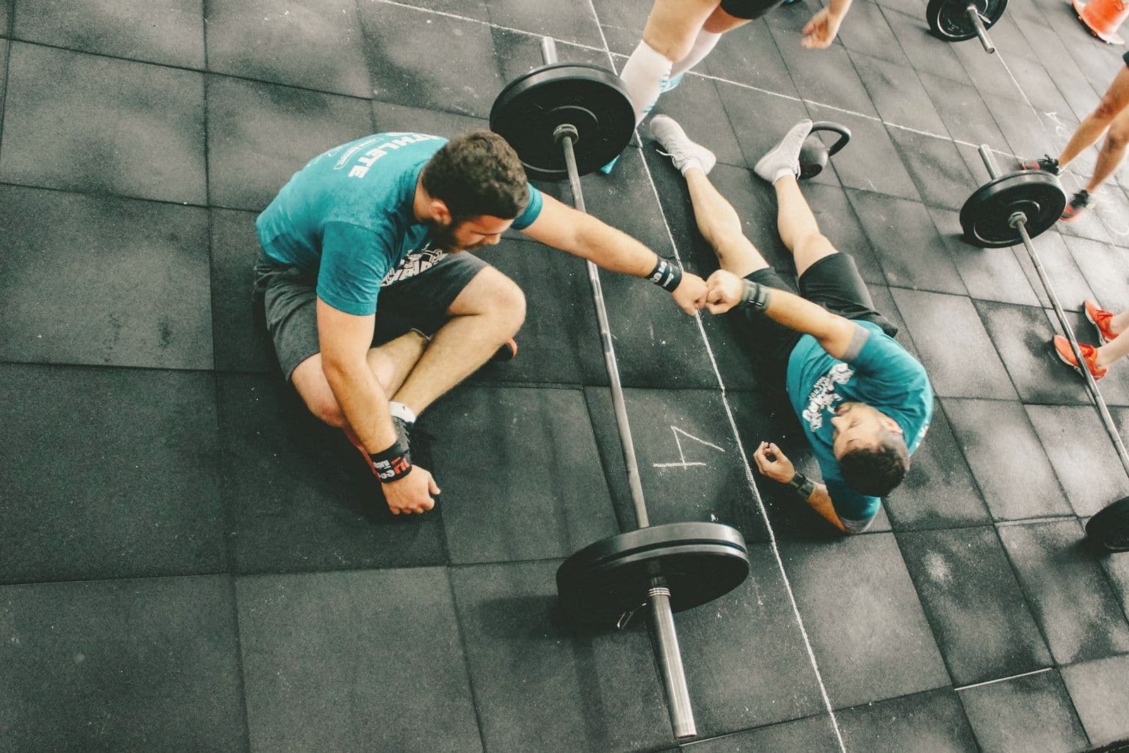 Two people fist-bumping on a gym floor after a set