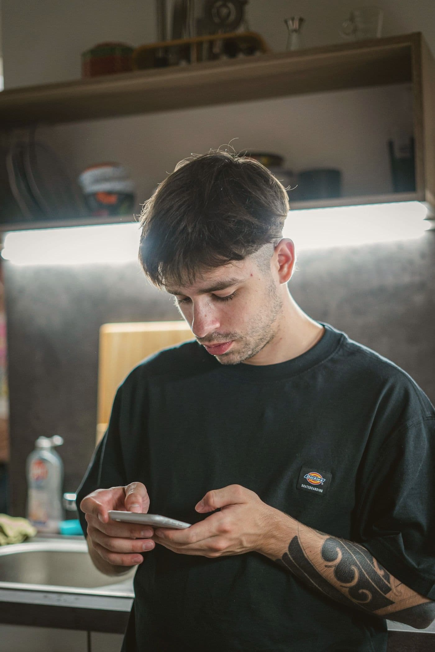Someone standing in a kitchen, looking at their phone