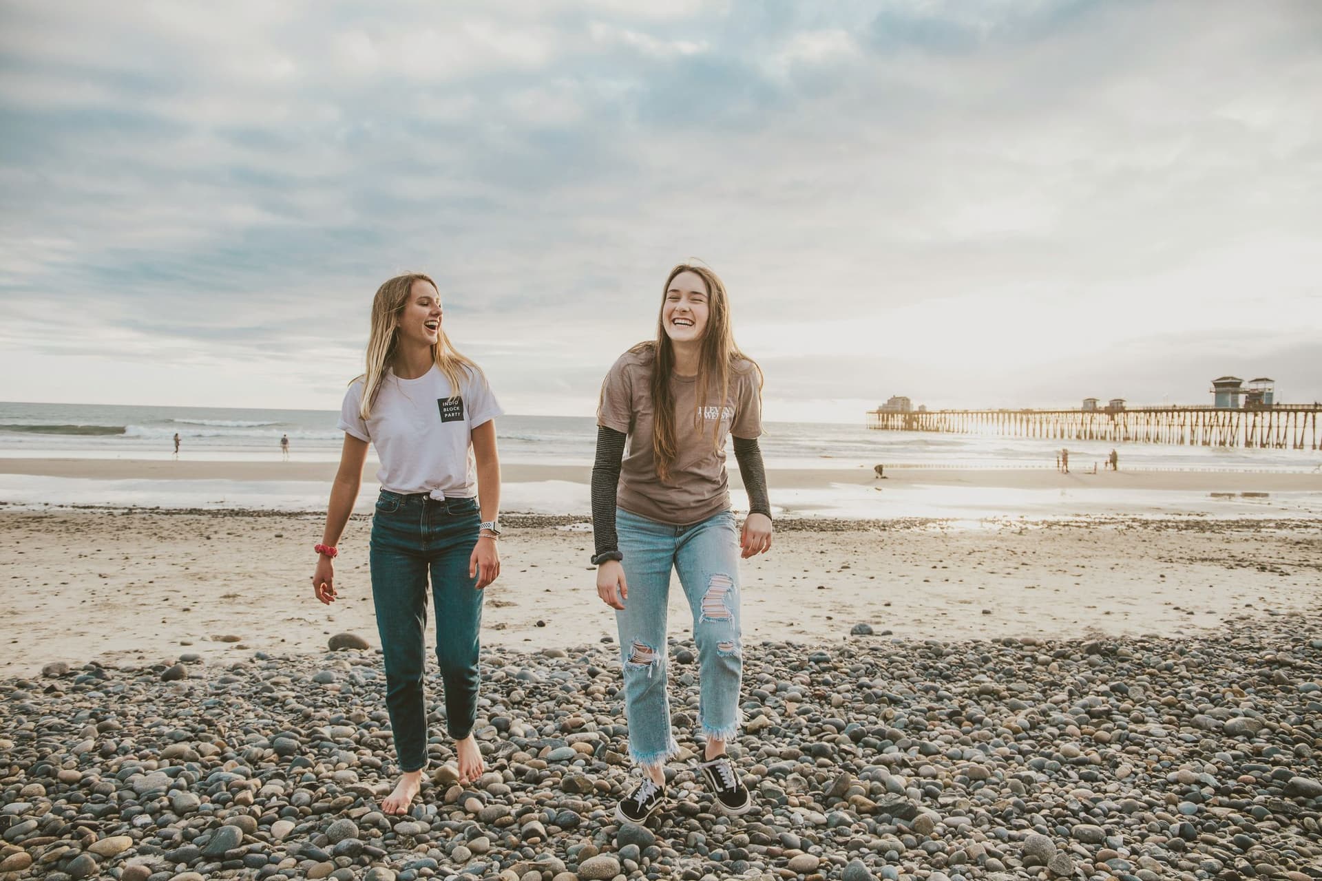 Two friends walking and talking on a pebble beach at dusk